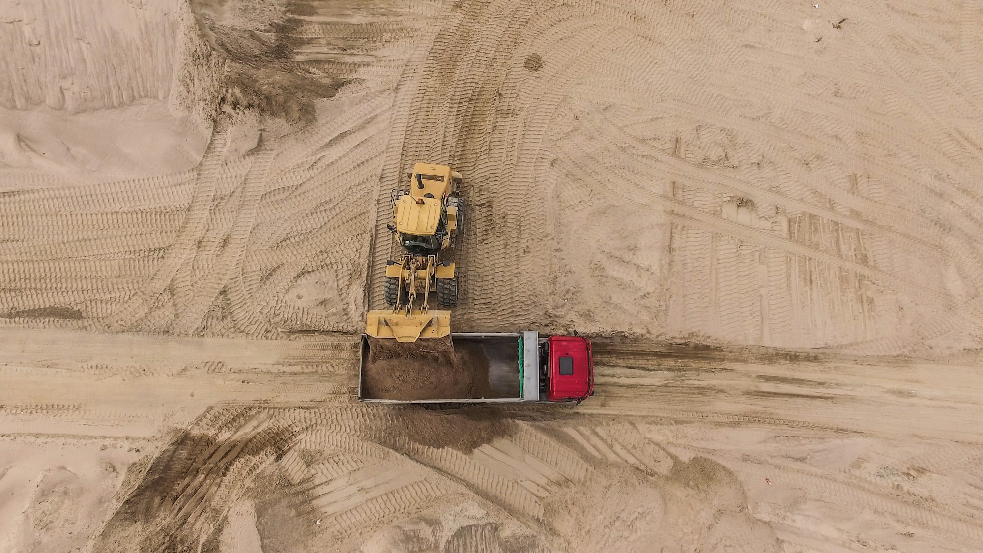 Aerial view of bulldozer pouring sand into truck